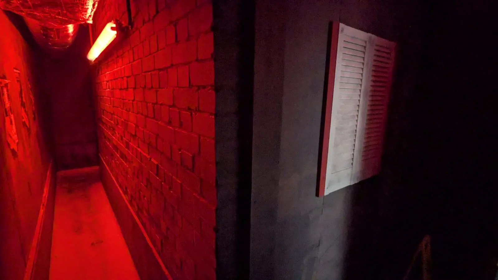 Inside The Lamorna Brown Affair: a red-lit brick corridor